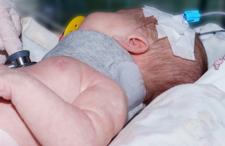 Doctor holding phonendoscope and doing auscultation newborn baby
